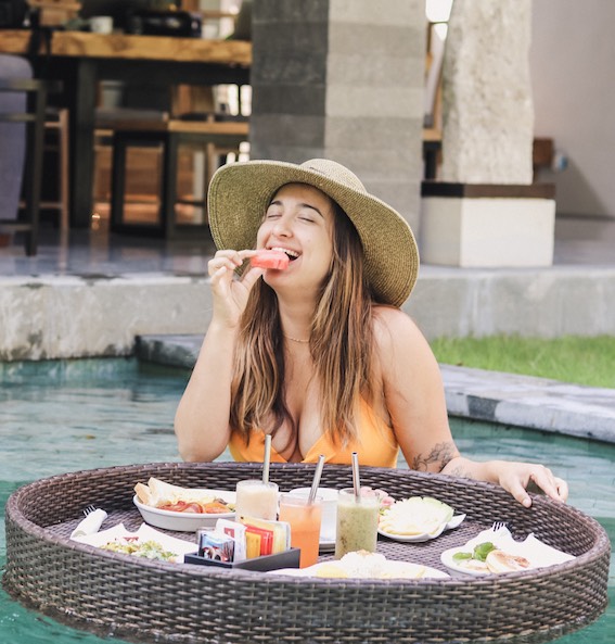 girl with hat on eating fruit at floating breakfast in Bali hotel pool